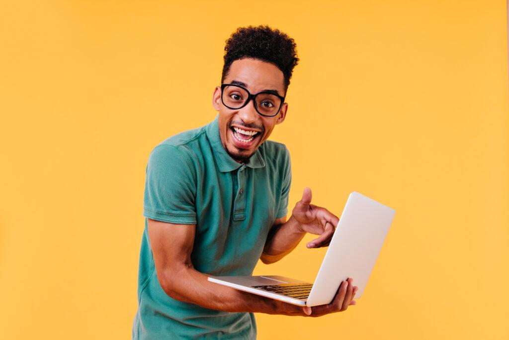 blithesome student green t shirt posing with laptop indoor photo amazed male freelancer isolated